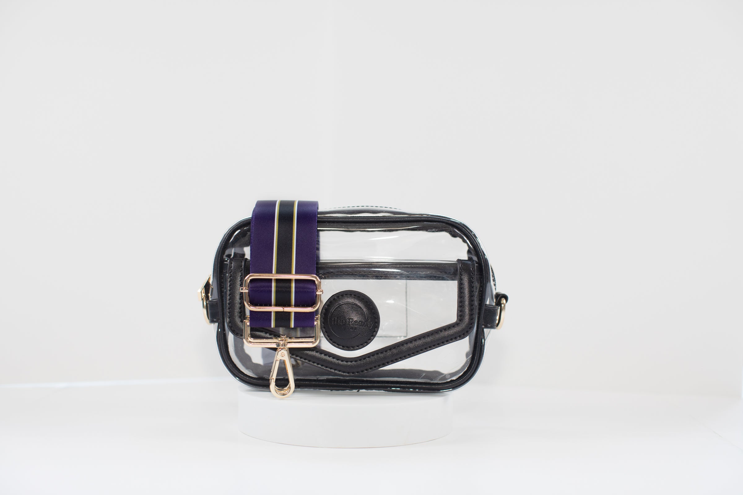 Clear stadium bag with black leather trim, front facing, with a crossbody strap in team colors of the Baltimore Ravens.