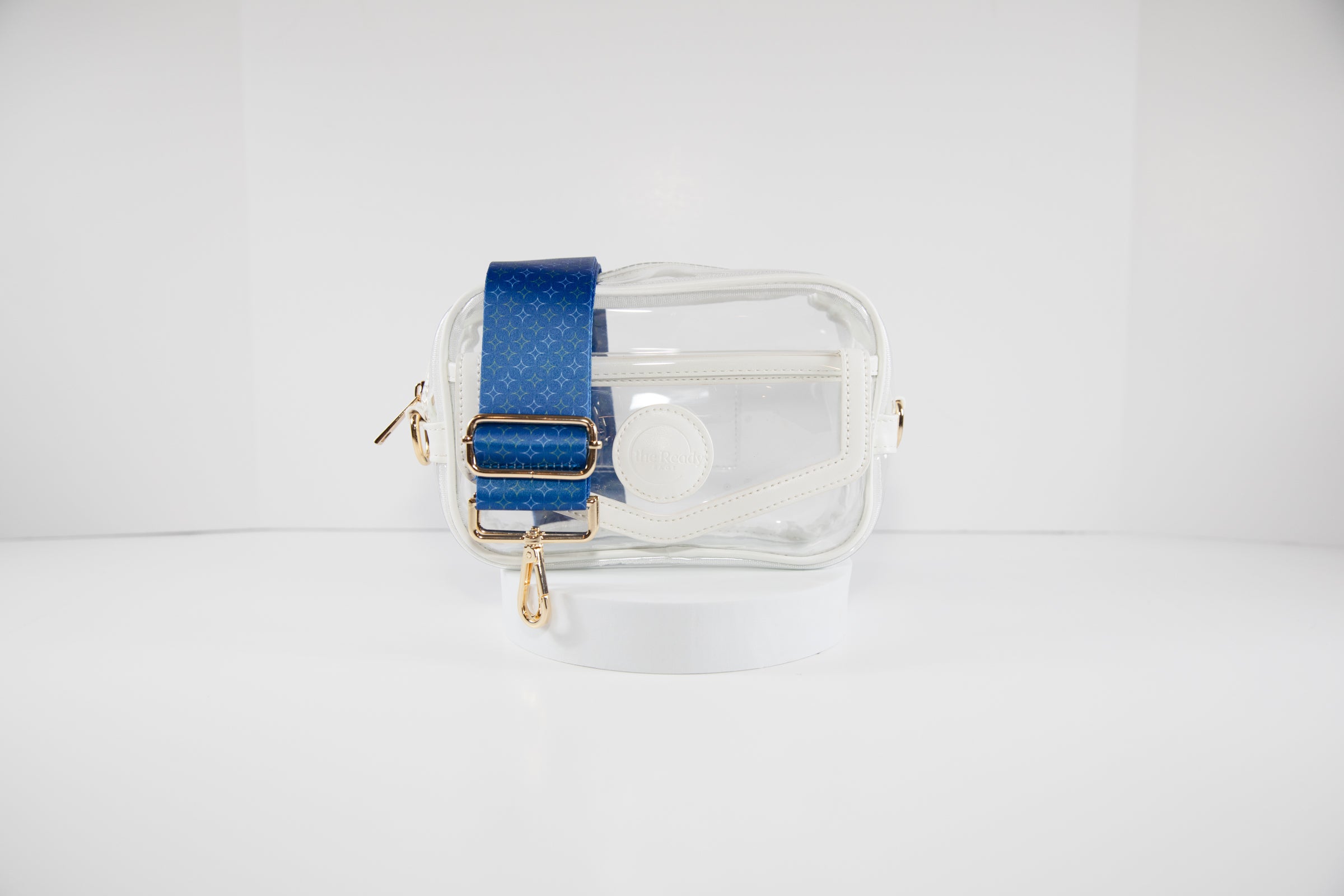 Clear stadium bag with white leather trim shown with a crossbody strap in Kansas City Royals team colors of navy and gold.